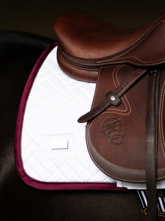 Side view of the back of the Merlot Equestrian Stockholm Modern White Jump Pad under a brown saddle