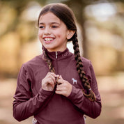 Front closeup view of a young model wearing the Burgundy Equinavia Lena Kids Long Sleeve Quarter Zip outdoors