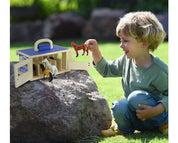 View of a young male model playing the with Breyer Breyer Farms Wood Carry Stable outside