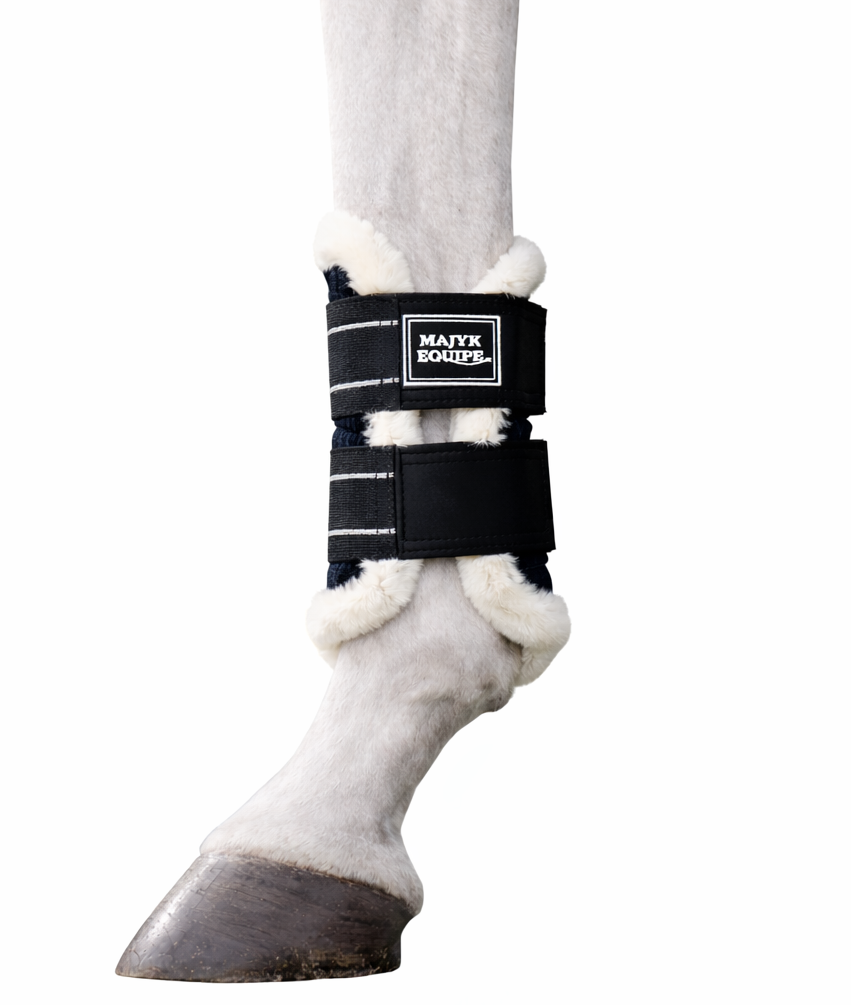 Side view of a black Majyk Equipe Aeroguard Fleece Edge Brushing Boot on a gray horse's leg on a white background