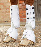 View of a horse wearing the white Premier Equine Carbon Tech Air Cooled Eventing Front Boots while standing on a pea gravel path