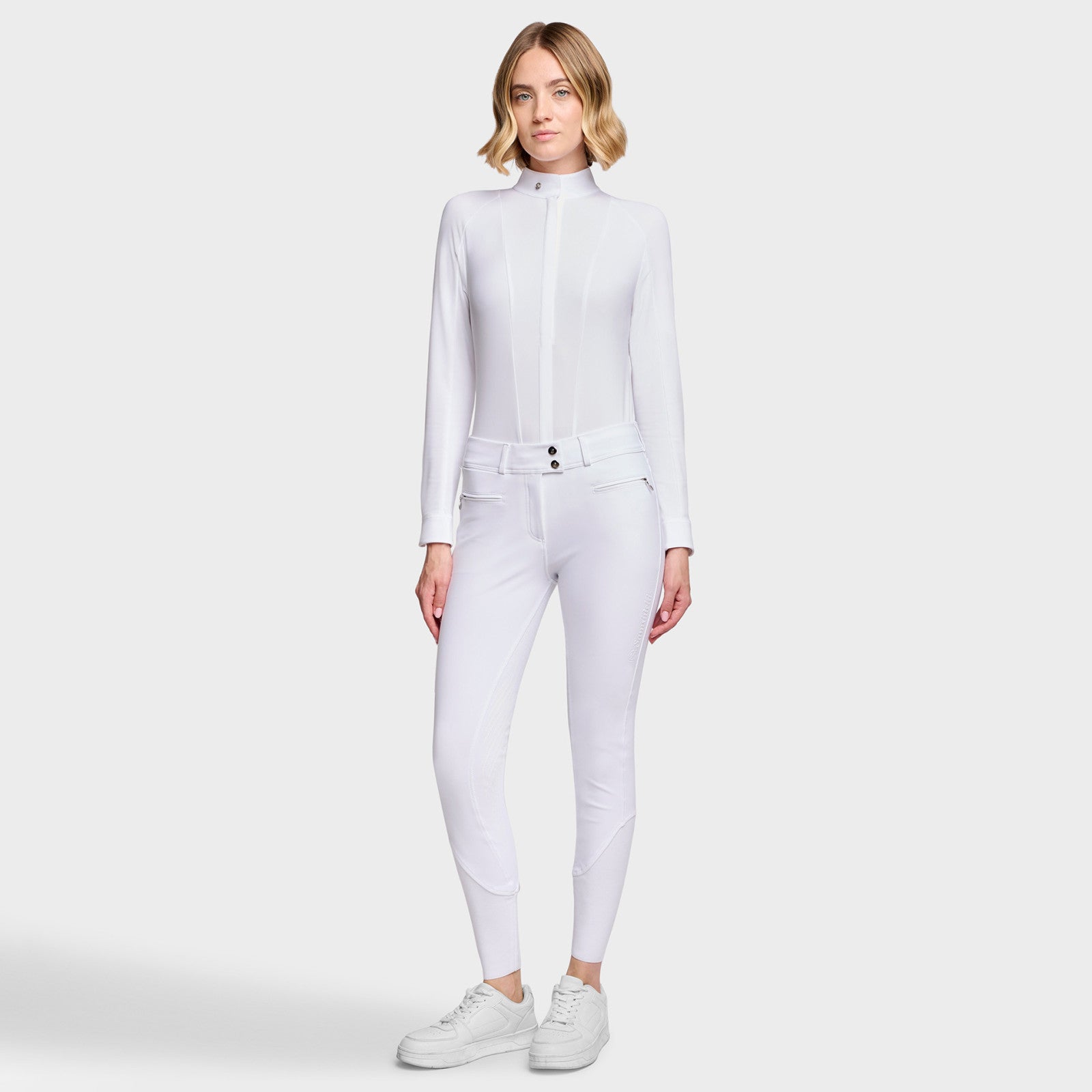 Full body front view of a female model wearing the White Samshield Chloe 3D Full Grip Breeches with a white shirt on a plain background