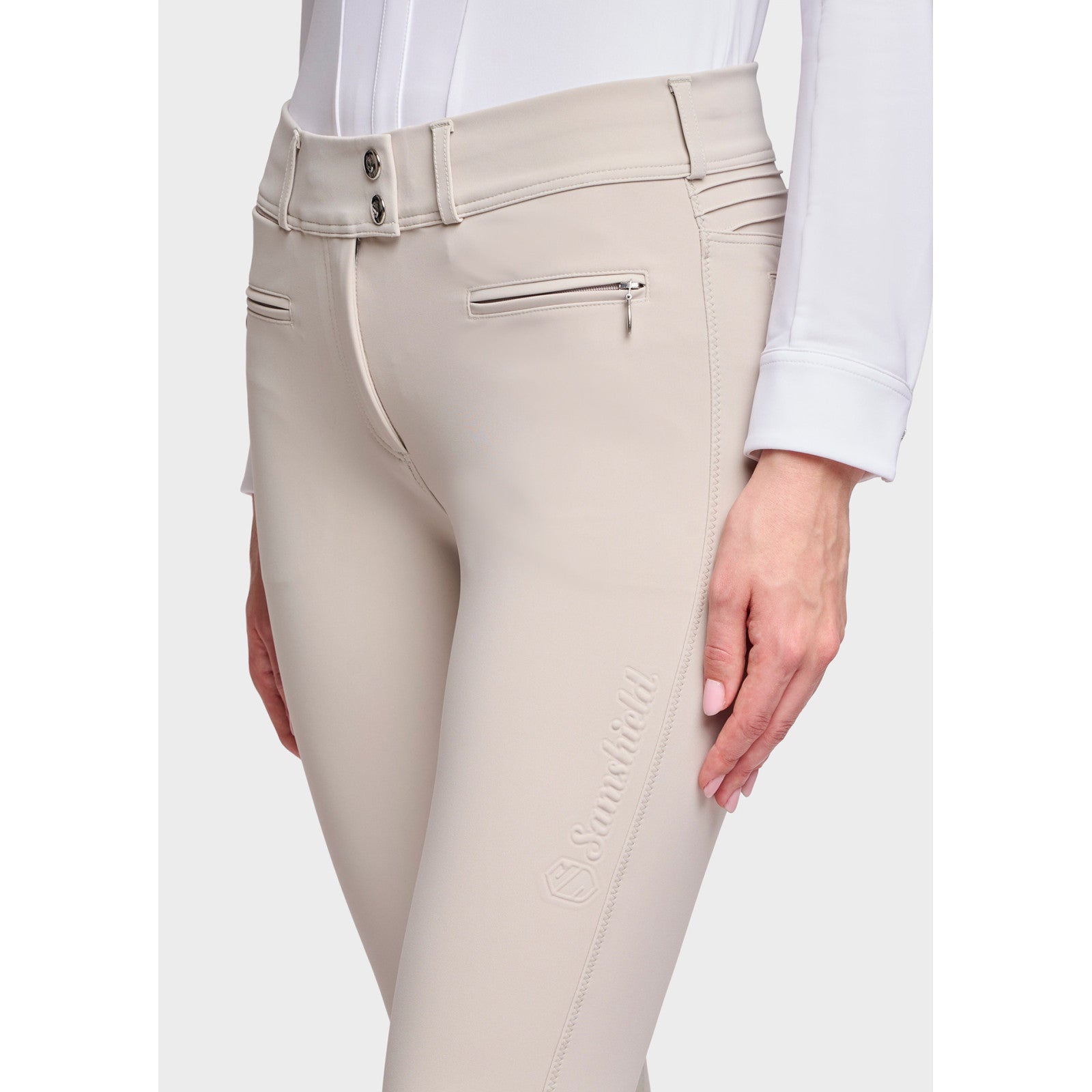 Close-up angled front view of a female model wearing the Beige Samshield Chloe 3D Knee Grip Breeches on a plain background