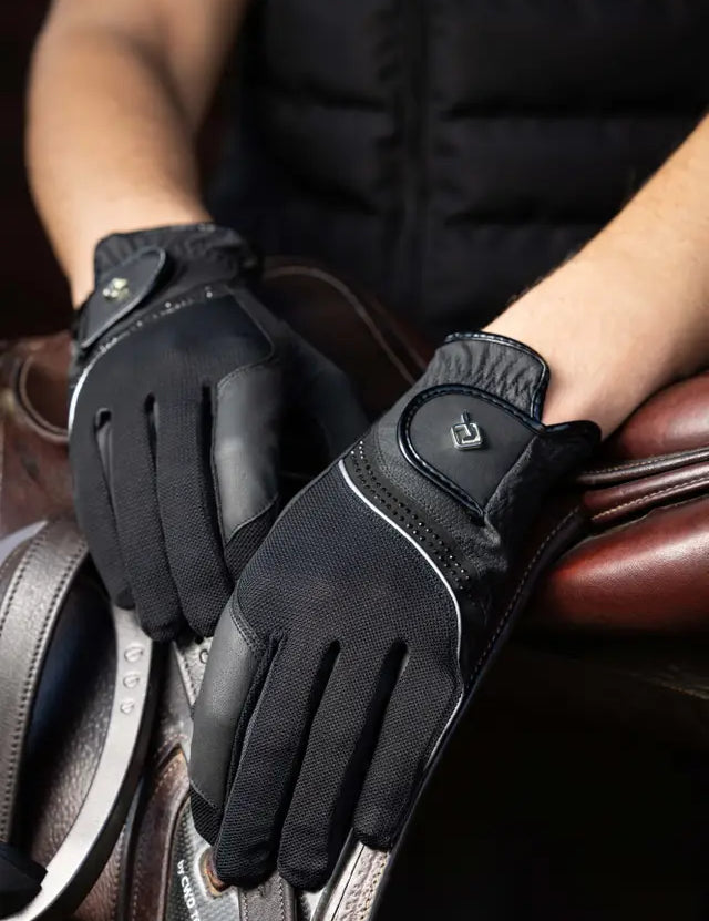 Person wearing black LeMieux Crystal Gloves with hands laid over english saddle