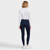 Full body back view of a female model wearing the Navy Samshield Delice Floral Full Grip Breeches with white shirt on a plain background
