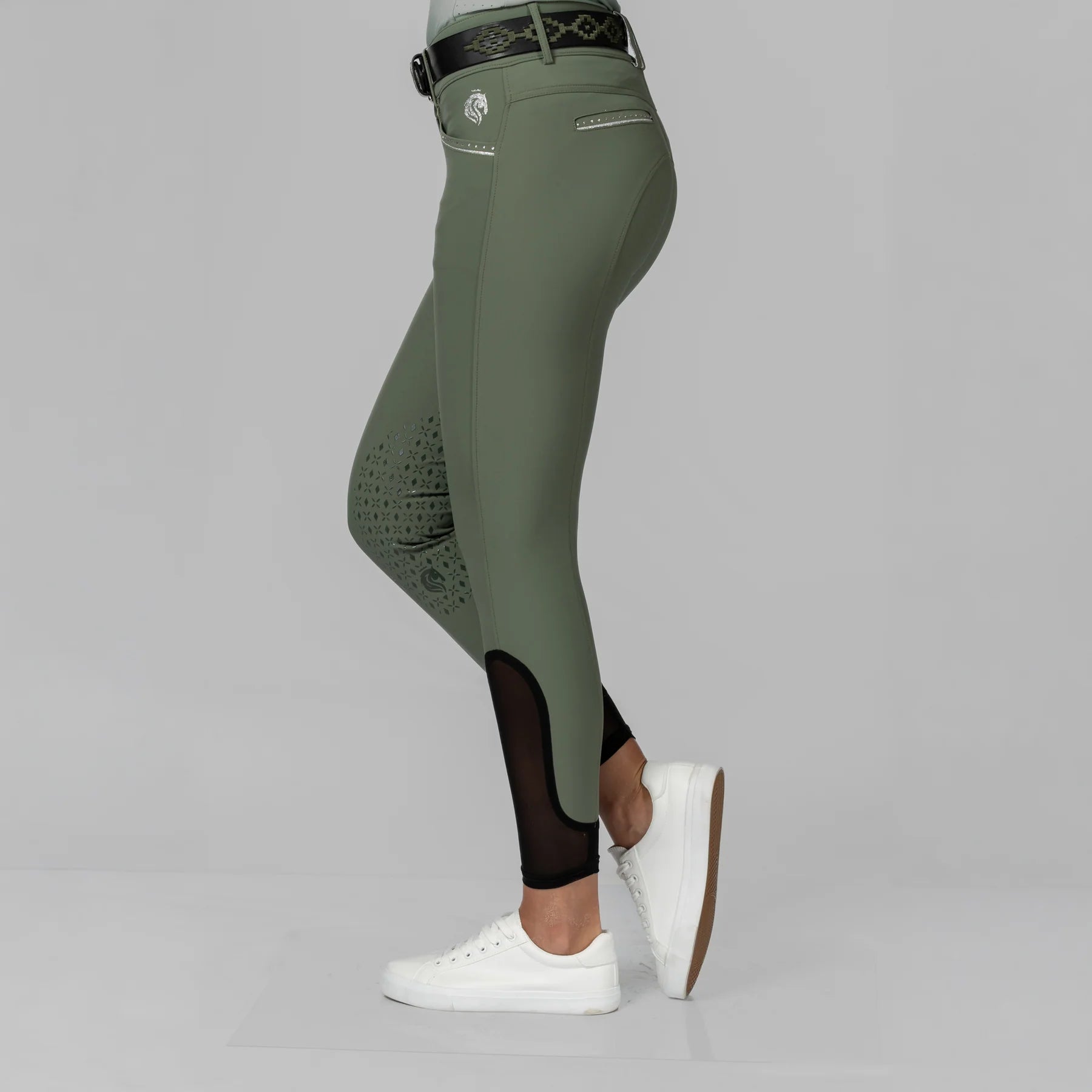 Side view of a model wearing the Thyme/Silver Equinavia Victoria Knee Patch Breeches on a plain background