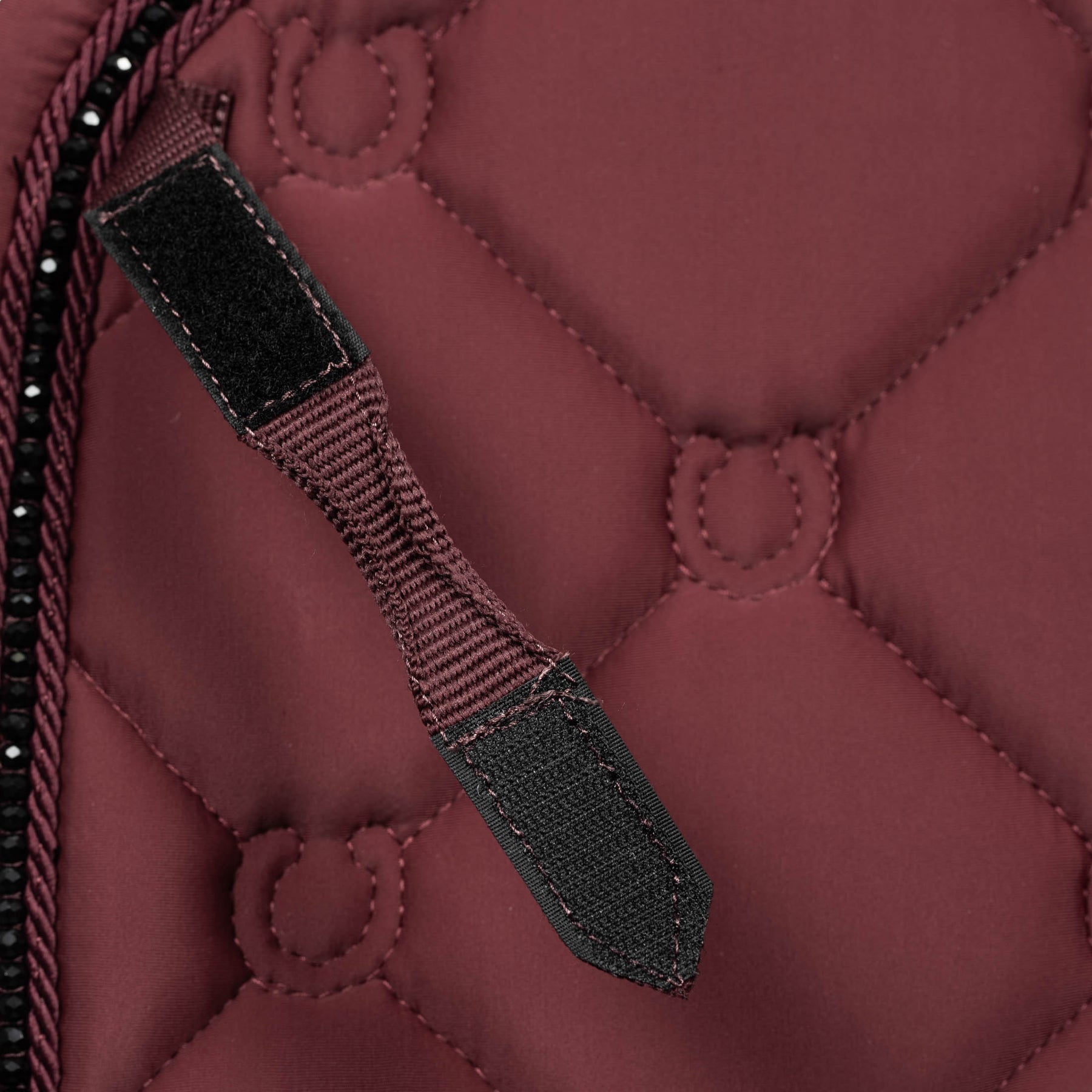 Close-up view of the D Ring keeper on the burgundy Equinavia Bergen Crystal Dressage Saddle Pad