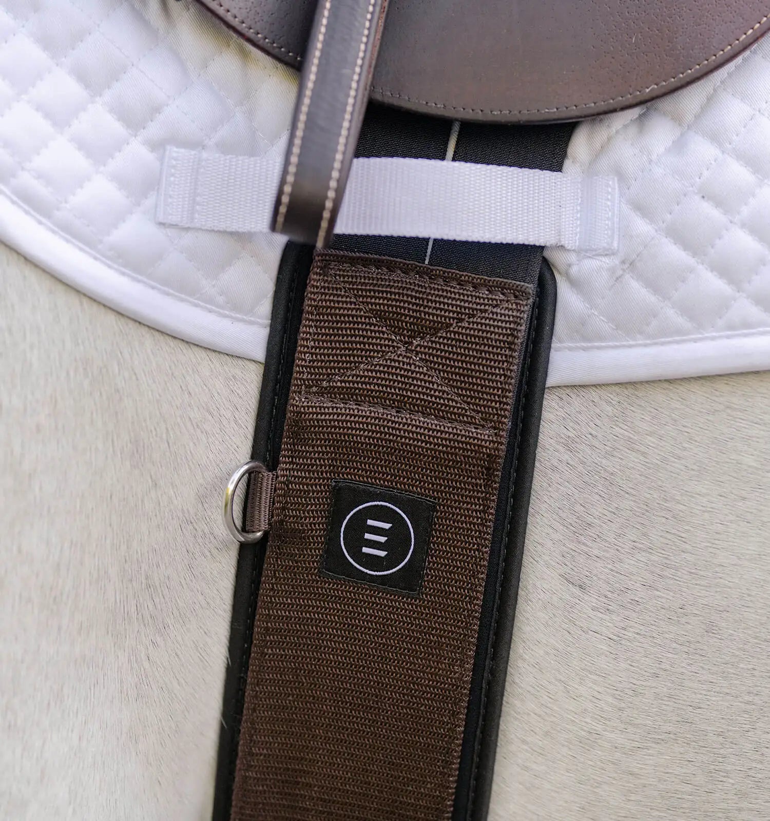 Brown fabric english girth shown on grey horse