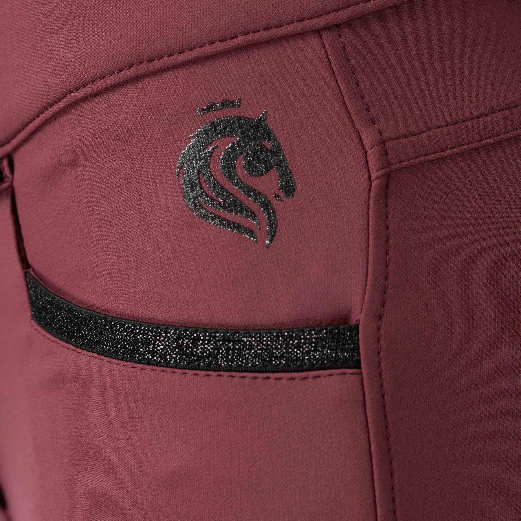 Side closeup view of the Burgundy Equinavia Kristina Full Seat Breeches on a plain background showing the pocket detail and Equinavia logo