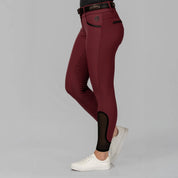 Side view of a model wearing the Burgundy Equinavia Kristina Full Seat Breeches on a plain background