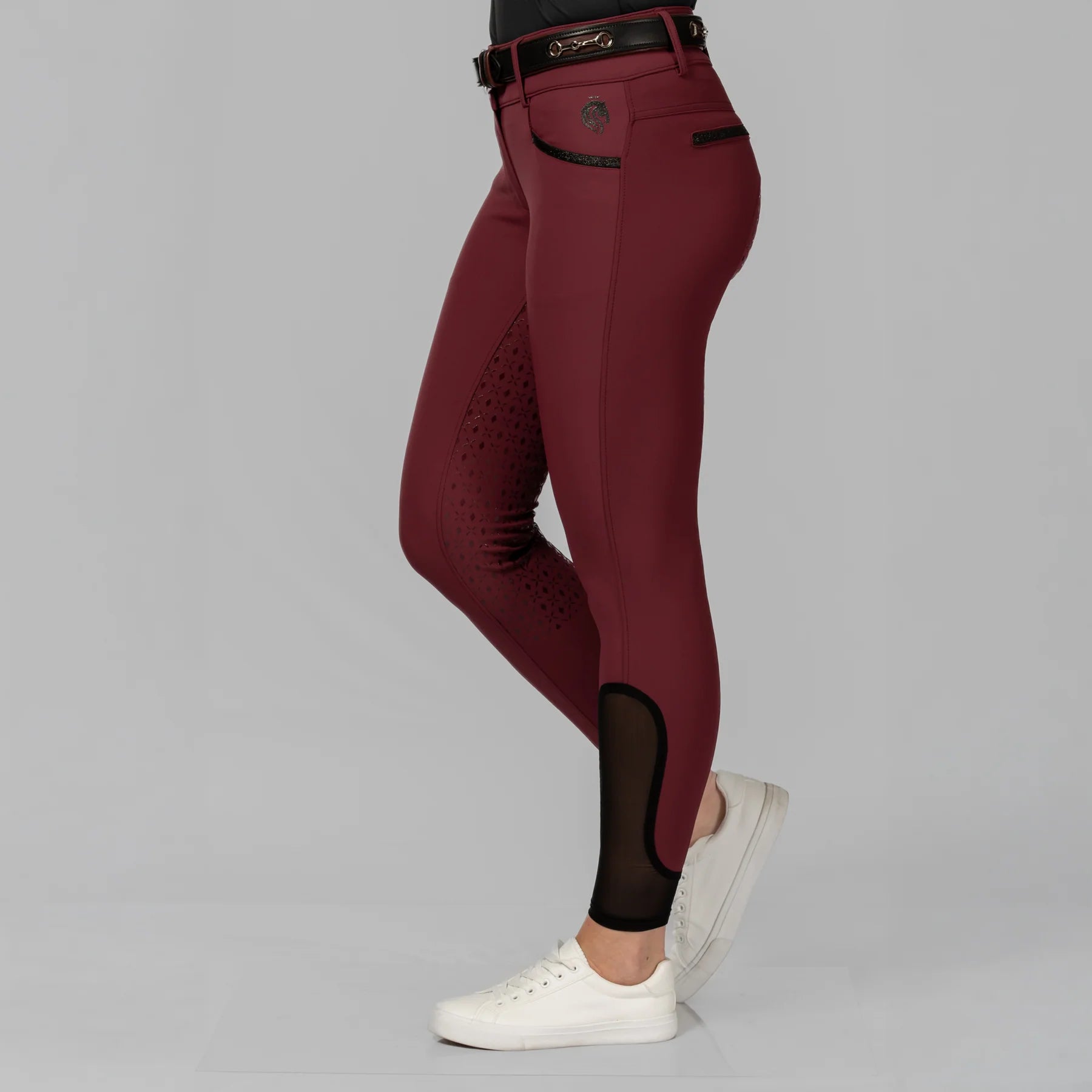 Side view of a model wearing the Burgundy Equinavia Kristina Full Seat Breeches on a plain background