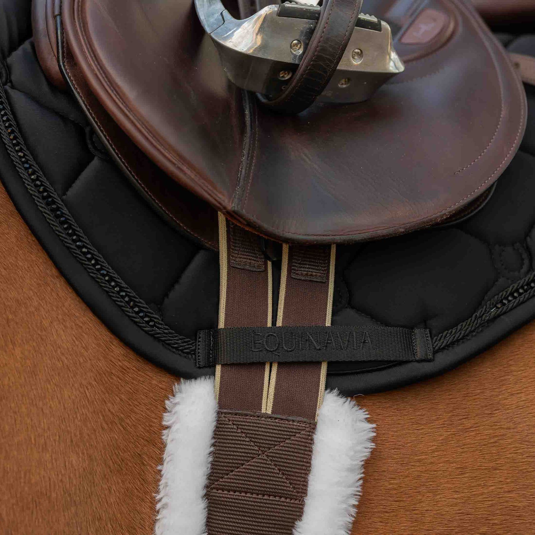 Close-up side view of the Black Equinavia Bergen Crystal All Purpose Pad under a brown saddle