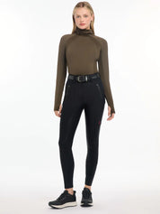 Full body front view of a model wearing the black DryTex Waterproof Full Seat Breeches, green top, and black shoes on a white background