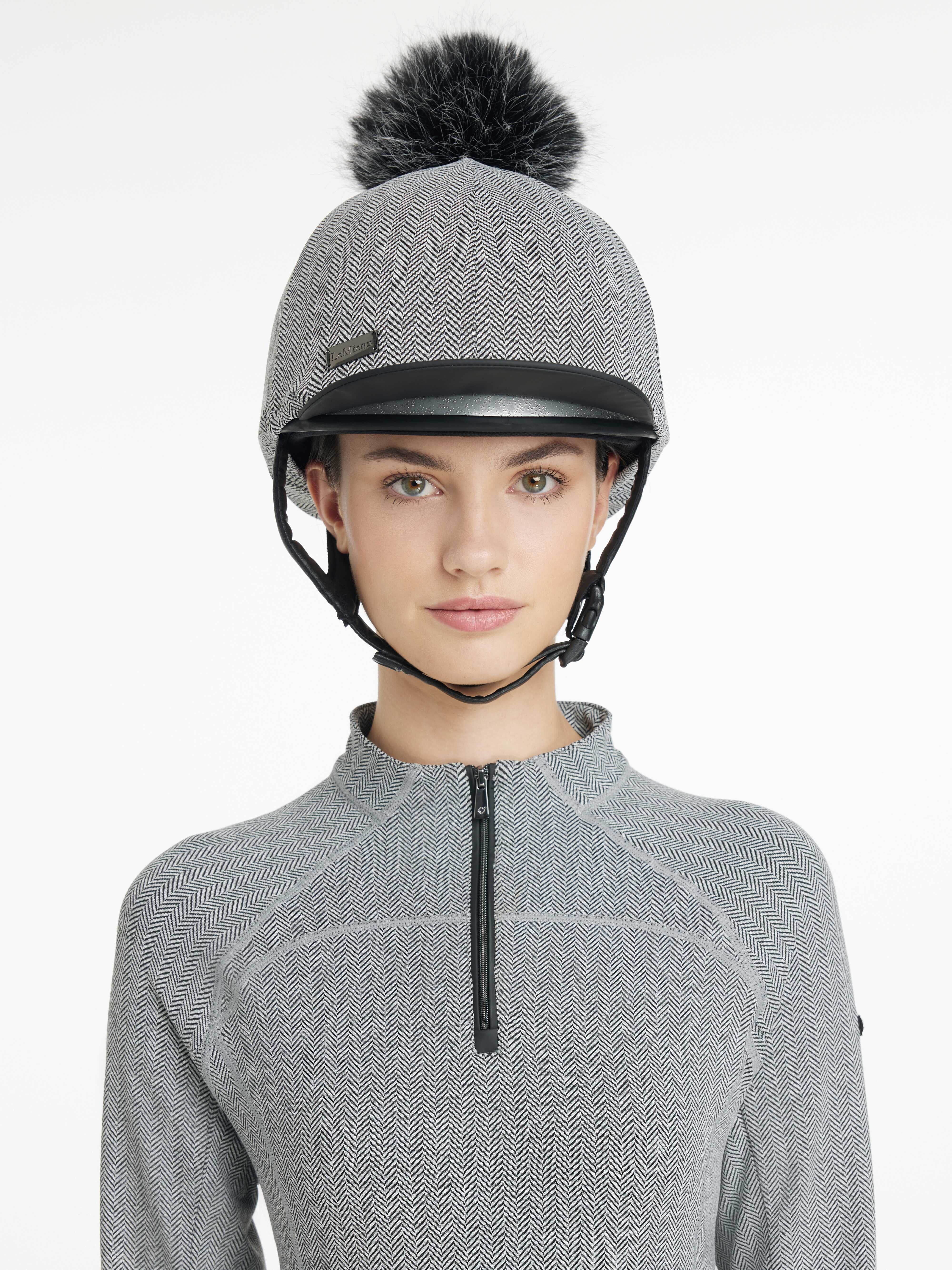 Front view of a female model wearing the Herringbone LeMieux Aspen Hat Silk over a helmet on a plain background