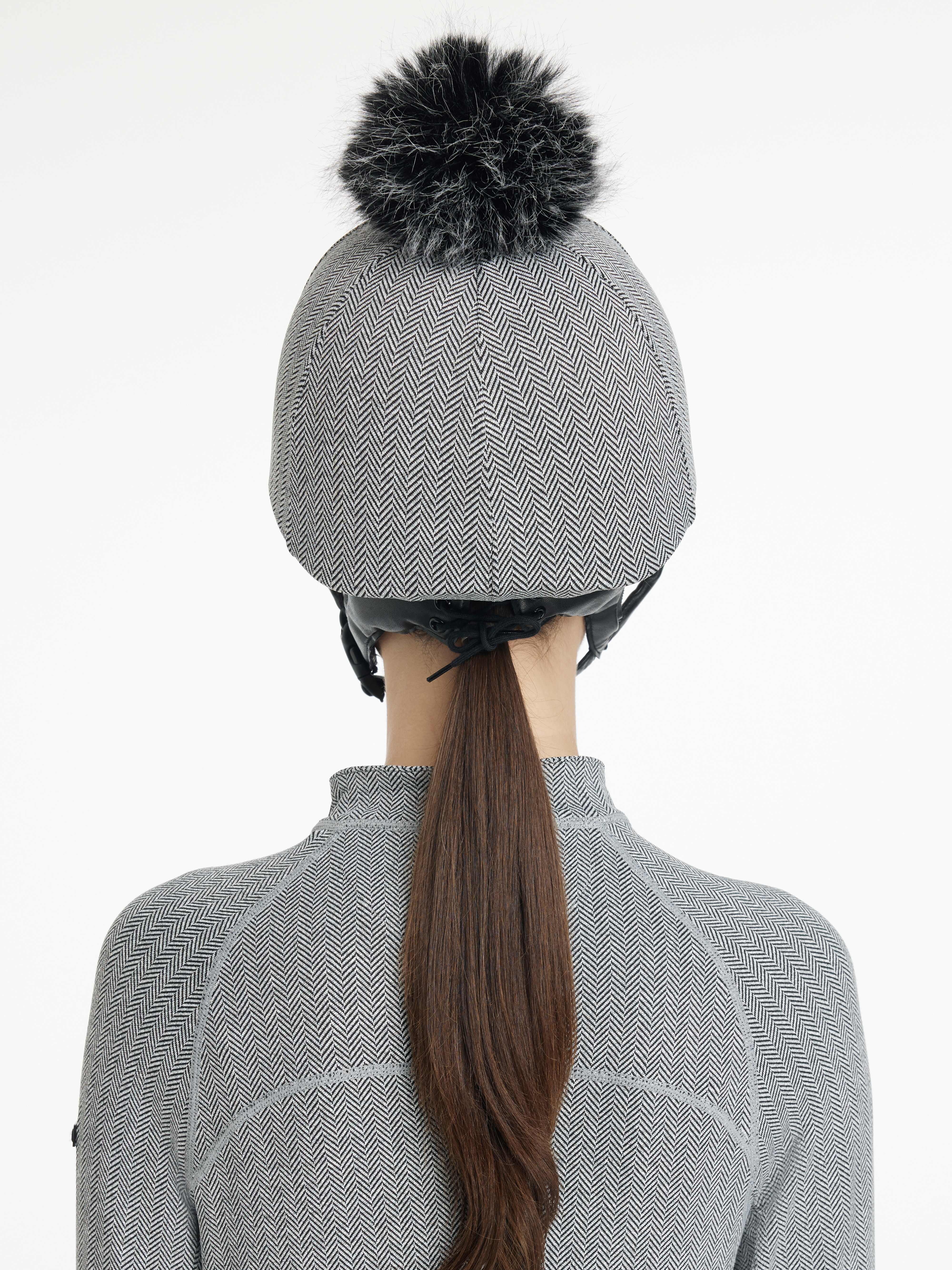Back view of a female model wearing the Herringbone LeMieux Aspen Hat Silk over a helmet on a plain background