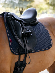 Angled side view of the navy LeMieux Brilliance Dressage Square worn by a horse under a black saddle