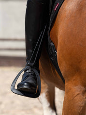 View of a model riding a horse with their foot in the LeMieux VectorFlex Stirrup