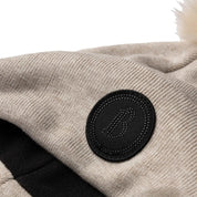 Close-up view of the "B" patch on the beige B Vertigo Sydney Knitted Hat on a white background