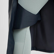 Side closeup view of a model wearing the Navy Horze Hazel Womens Long Raincoat on a plain background showing the leg straps inside