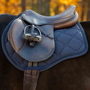 Side view of a horse wearing the Navy Equinavia Bergen Crystal All Purpose Pad under a brown saddle