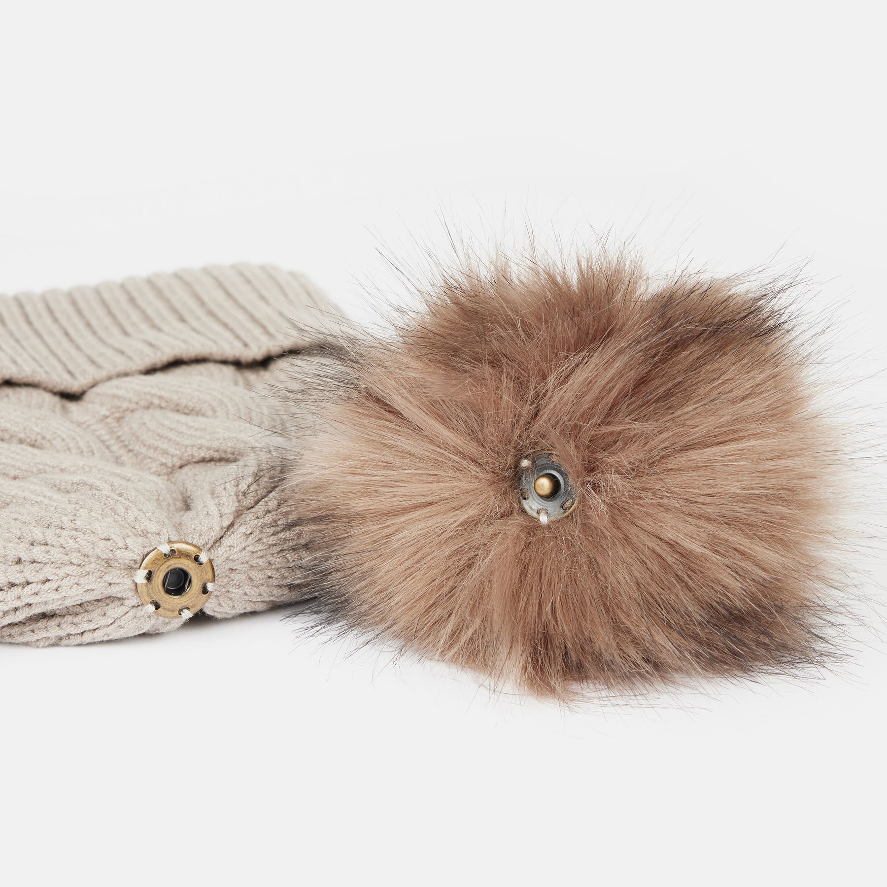 View of the removable pom on the Atmosphere Horze Anni Knitted Hat on a white background