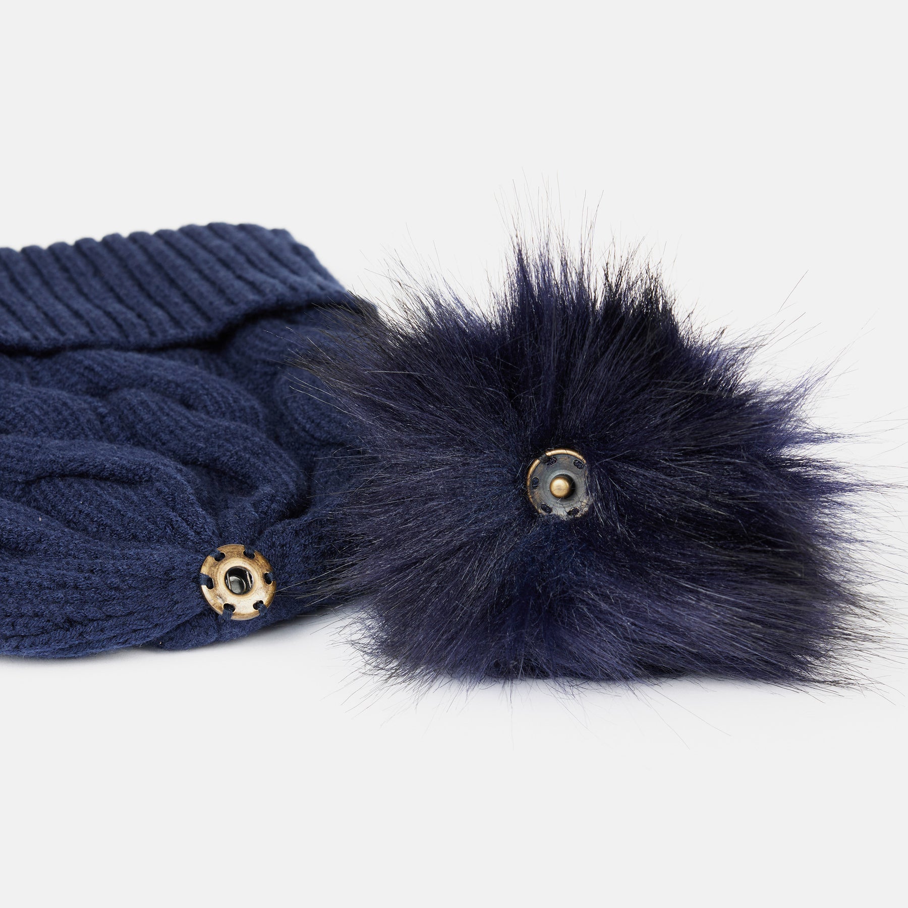 View of the removable pom on the Seaborne Navy Horze Anni Kids Knitted Hat on a plain background
