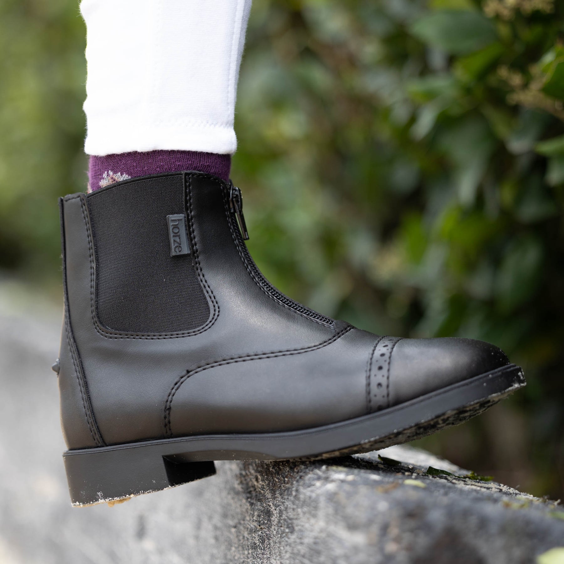 Side view of a young model wearing the Black Horze Wexford Kids Paddock Boots while standing outside