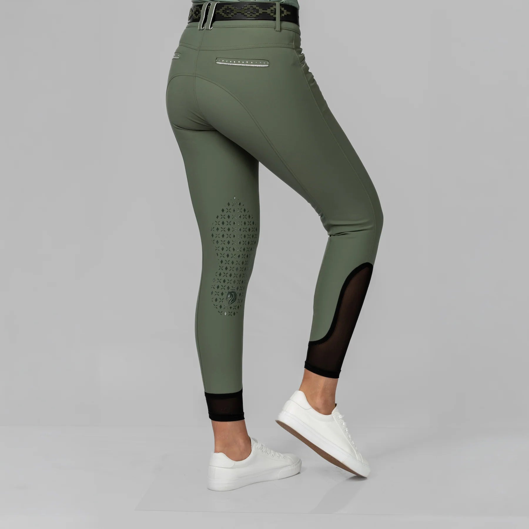 Angled back view of a model wearing the Thyme/Silver Equinavia Victoria Knee Patch Breeches on a plain background