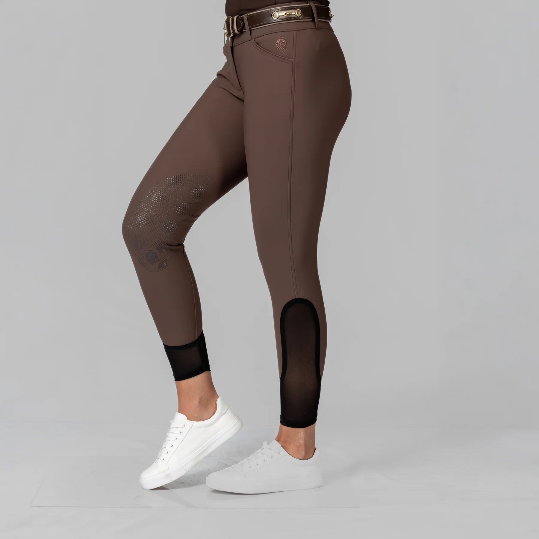 Side view of a model wearing the Dark Brown Equinavia Maud Tech Knee Patch Breeches on a plain background