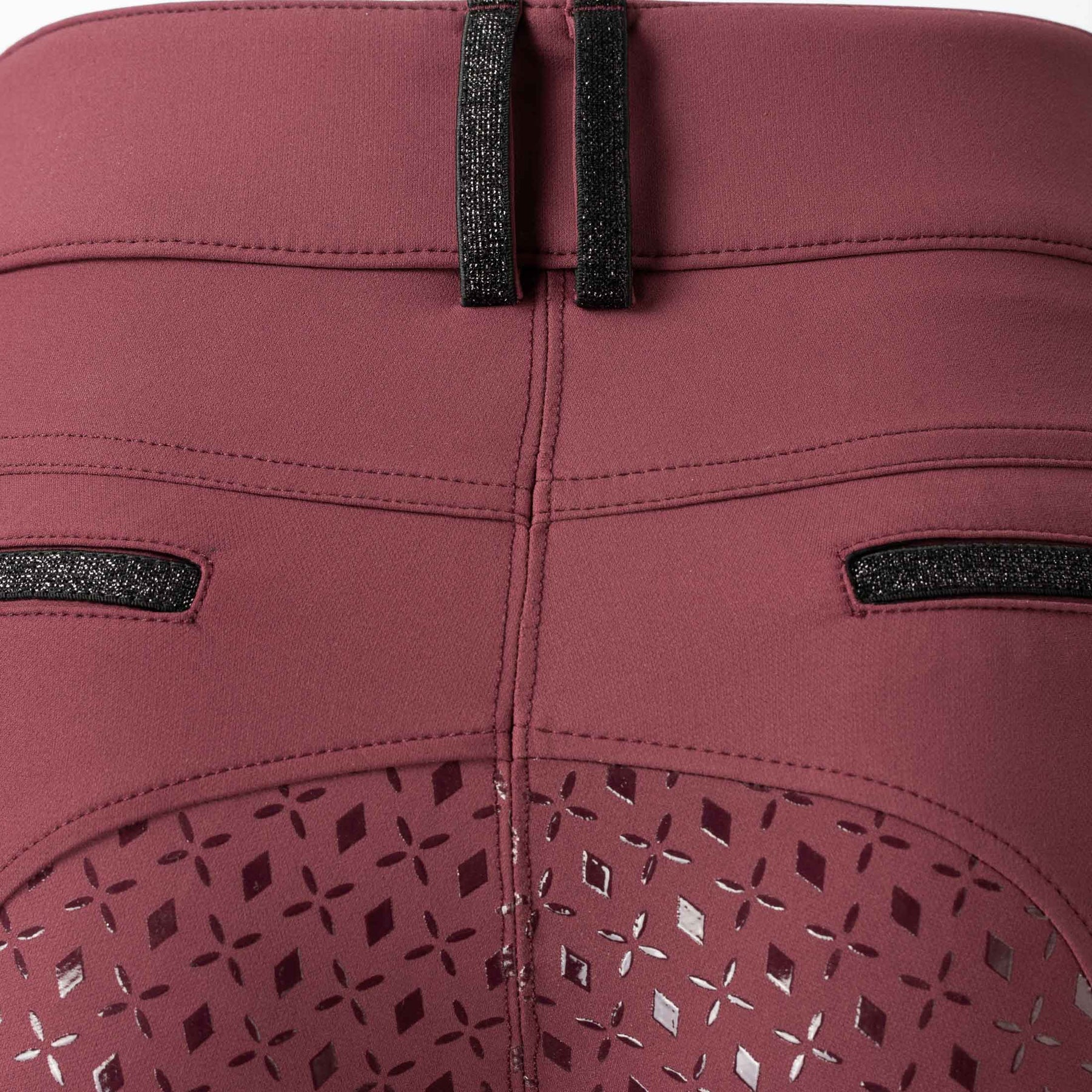 Back closeup view of the Burgundy Equinavia Kristina Full Seat Breeches on a plain background showing the belt buckle and silicone grip detail