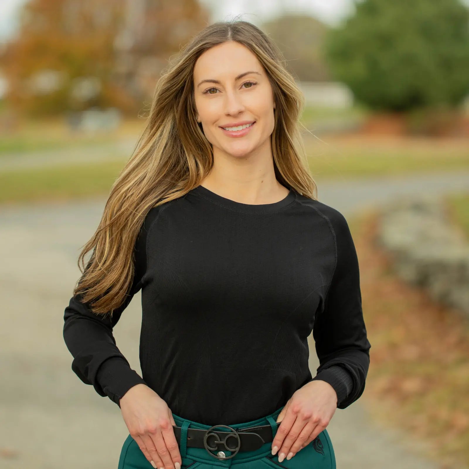 Front view of a model wearing the black Equinavia Dagny Leather Belt with a black top and green breeches while standing outside